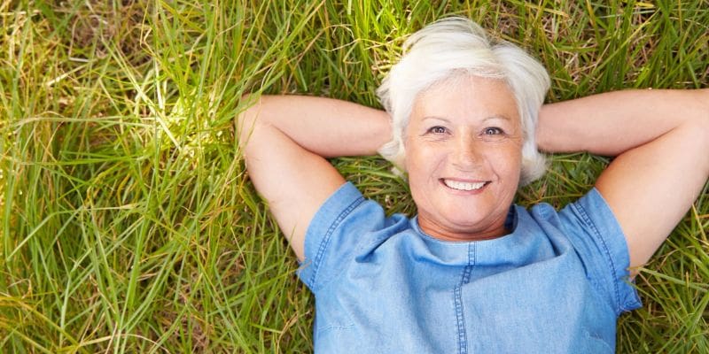 A woman laying in the grass smiling for the camera.