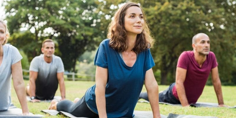 A woman is sitting on the ground in a park.