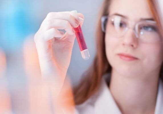 A woman holding a tube of red liquid.