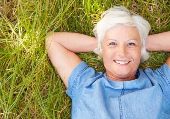 A woman laying in the grass smiling for the camera.