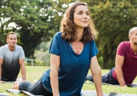 A woman is sitting on the ground in a park.